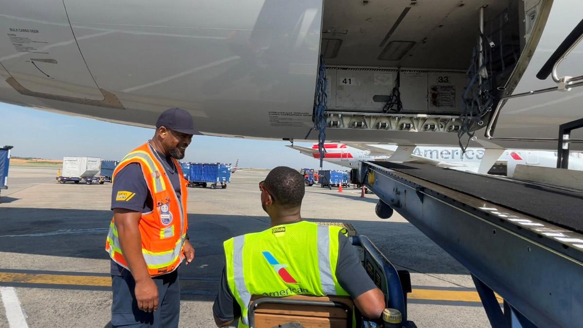 Two crew members talking to each other next to an aeroplane 