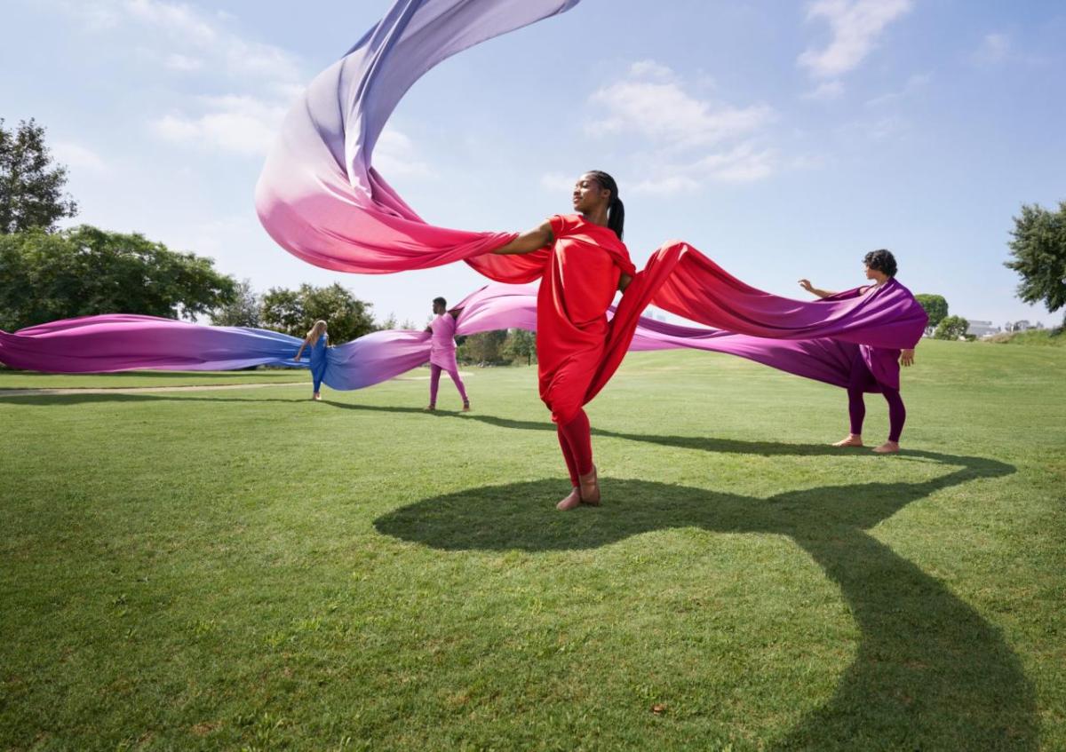 women dancing with colorful fabric on a lawn