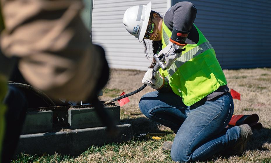 Georgia Hummel working on a power line outside on the ground.