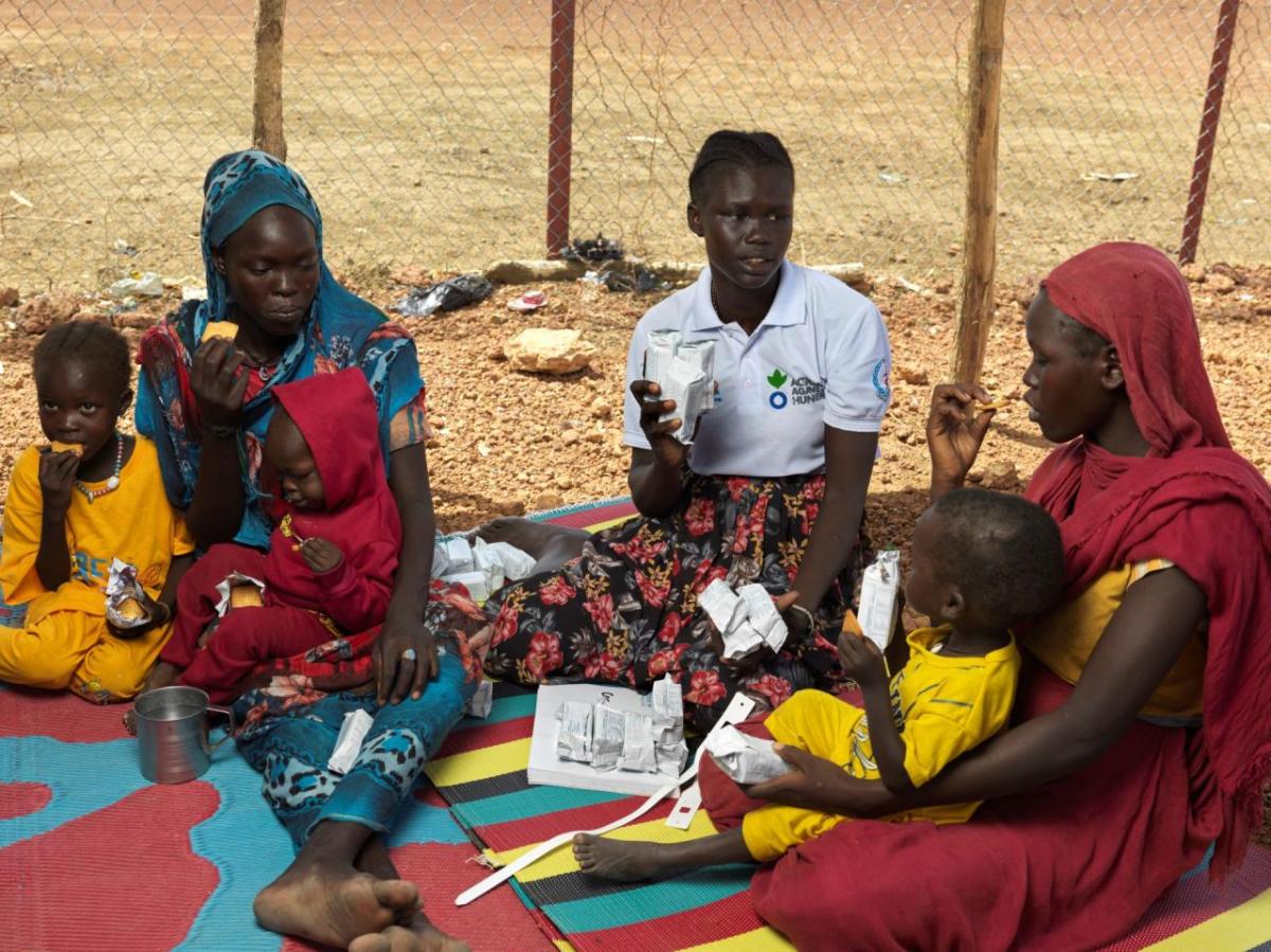 Mothers and children receiving care from Action Against Hunger worker