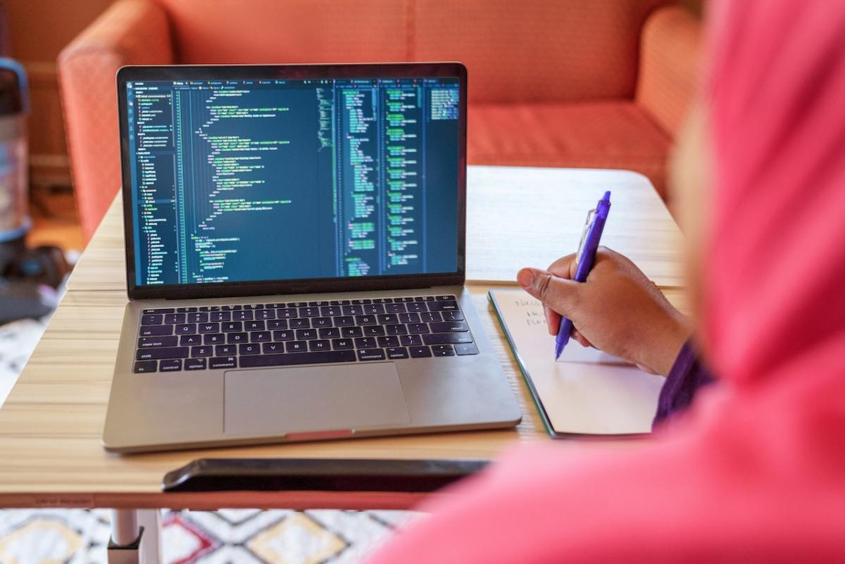 A person seated at a desk in front of a MacBook.