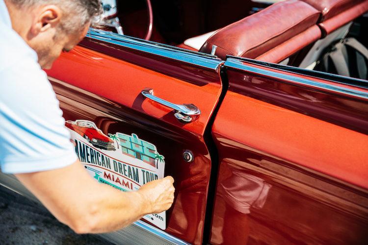 Man attaching a sign to the side of a car.