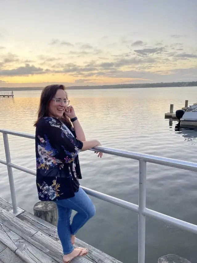 Jenny Oliveira on the edge of a dock looking over the water.