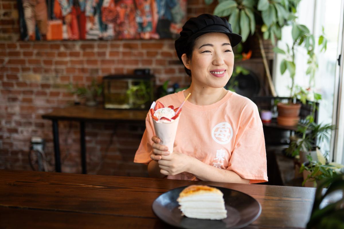 Mia Oi seated at a table with a milkshake.