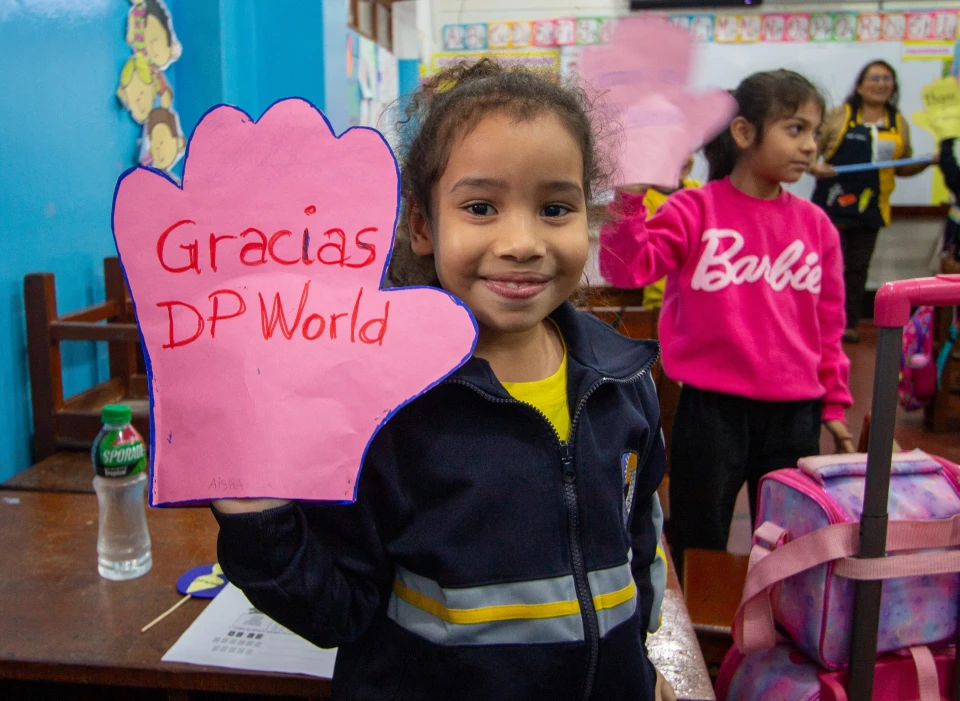 Child with artwork that says " Gracias DP World"