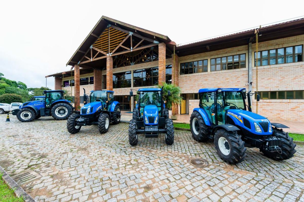 Blue New Holland tractors parked in front of a large building