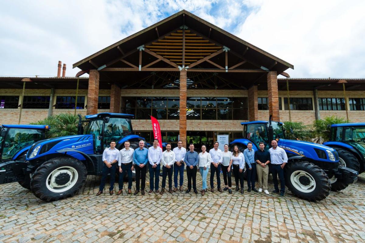 Group photo in front of blue New Holland tractors 