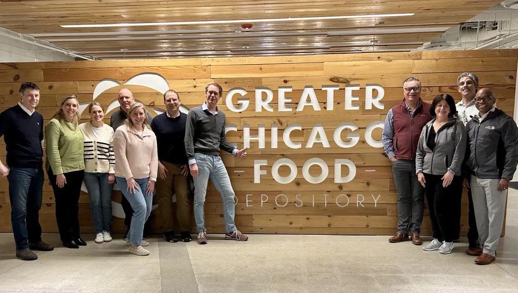 A group posed by a large sign "Greater Chicago Food Depository"