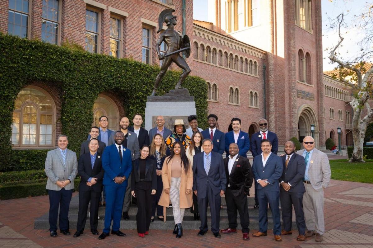 a large group of people stood together in front of a statue 