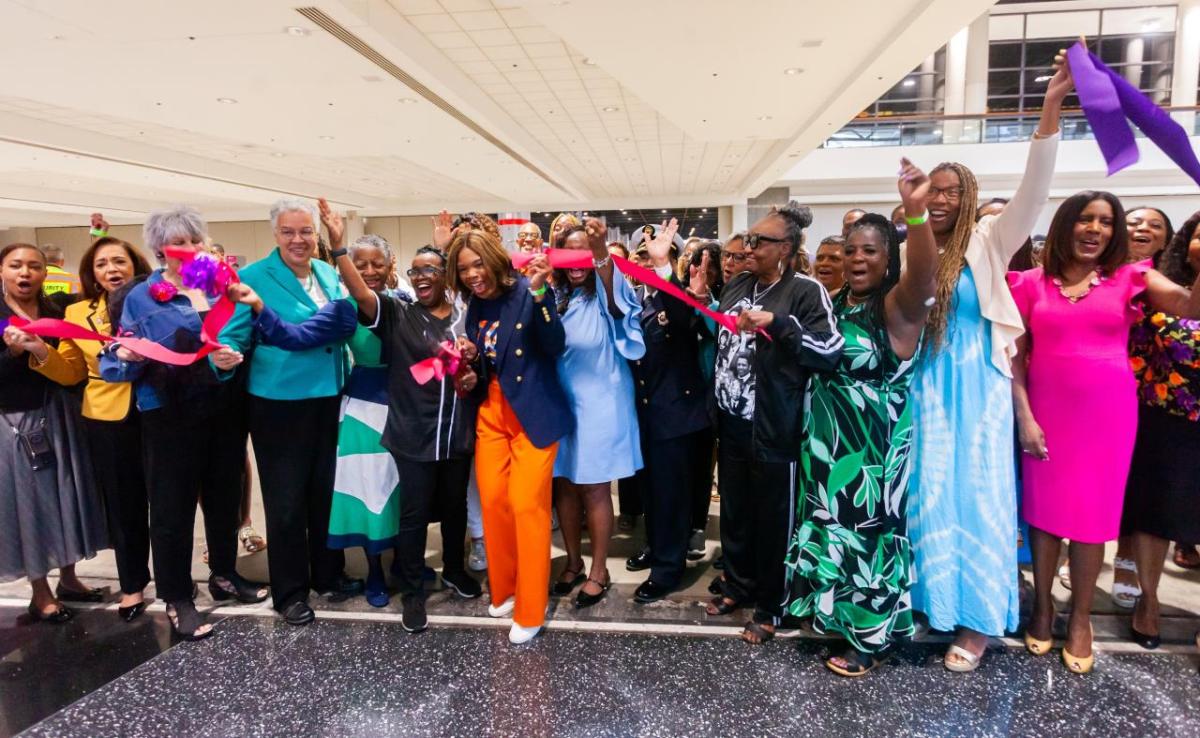 A group of people cheering at a ribbon cutting.