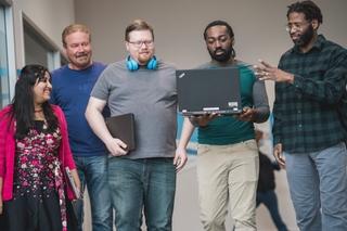 Five HARMAN employees holding laptops.