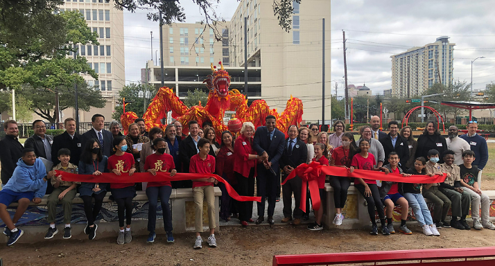 Large crowd of diverse people cutting a red ribbon