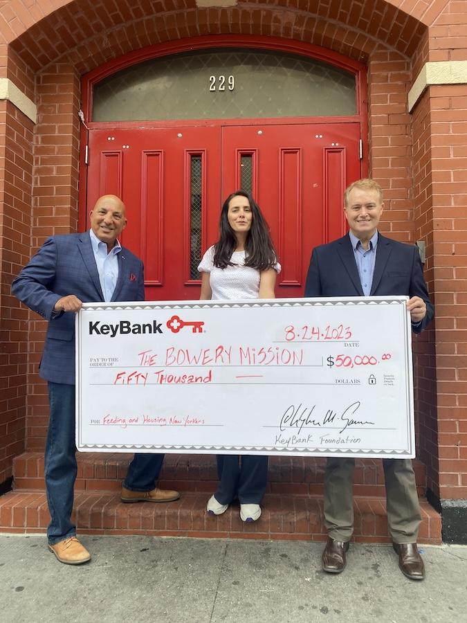 Representatives from KeyBank and The Bowery Mission shown holding a grant check for $50,000.