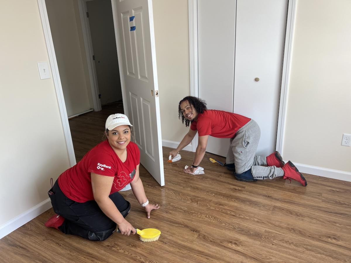KeyBank volunteers cleaning a floor inside of a newly built home.