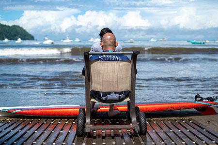 Person in wheelchair on the beach, looking out at the ocean