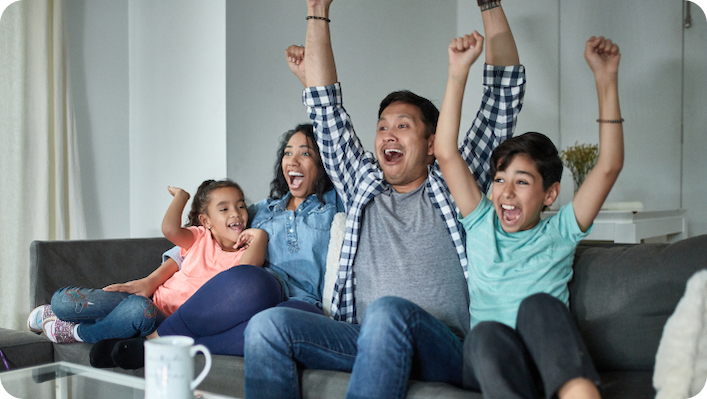 Family seated on a couch watching TV and cheering!