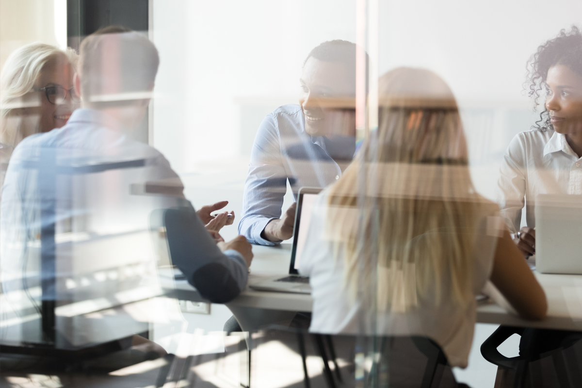 Group working at a conference table, seen through reflective glass