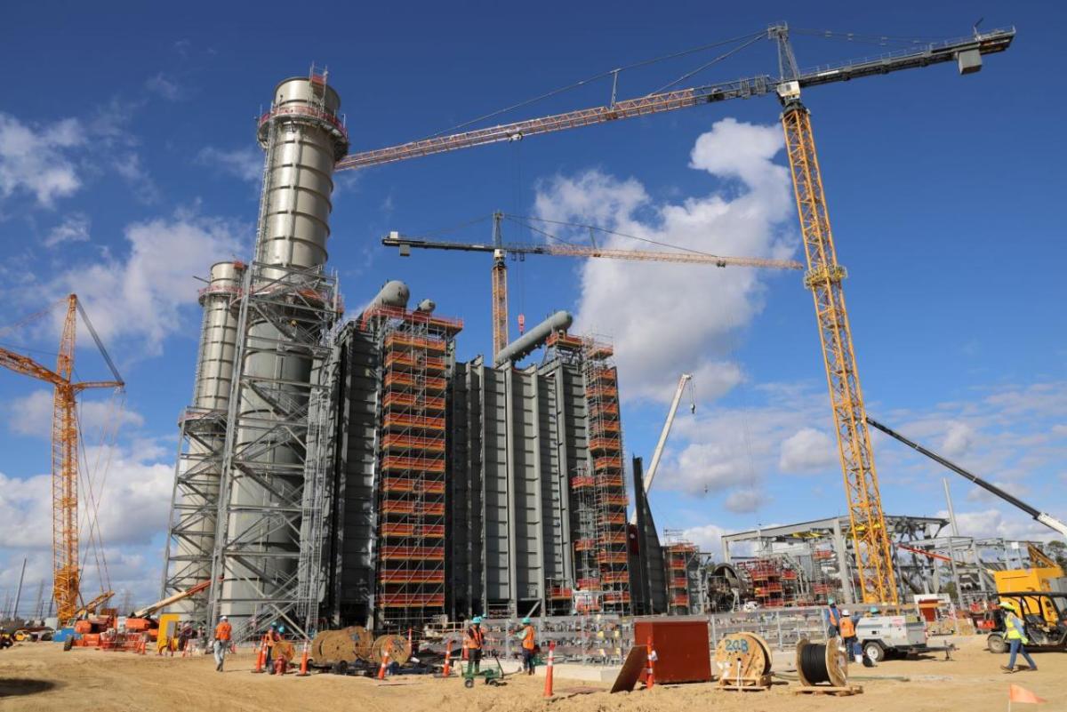 Numerous yellow cranes and massive industrial-style structures in Orange, Texas —a sign of progress on Entergy Texas’ Orange County Advanced Power Station " "