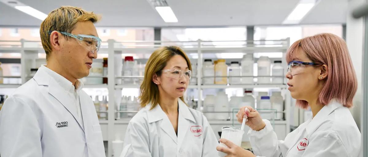 Three people in a lab environment looking at a substance.