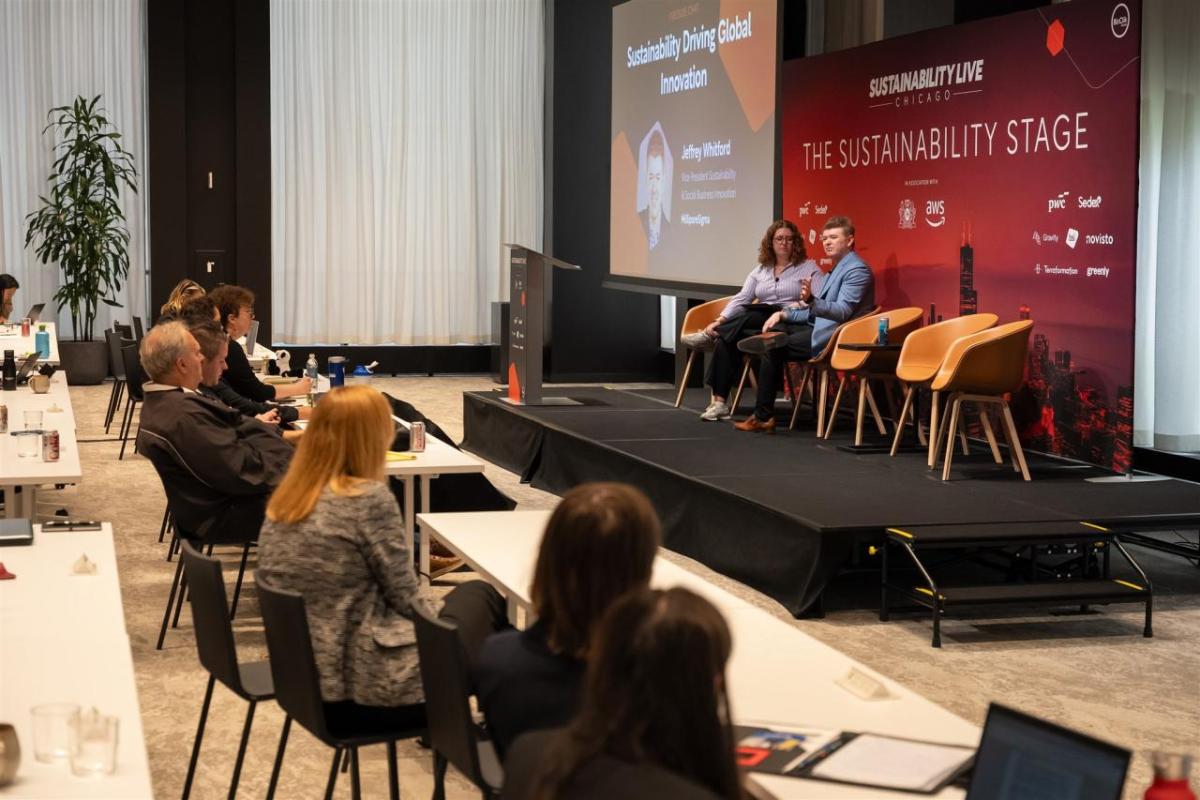 Wide shot of a fireside chat at Sustainability LIVE Chicago 205 with two people on stage and audience seated.
