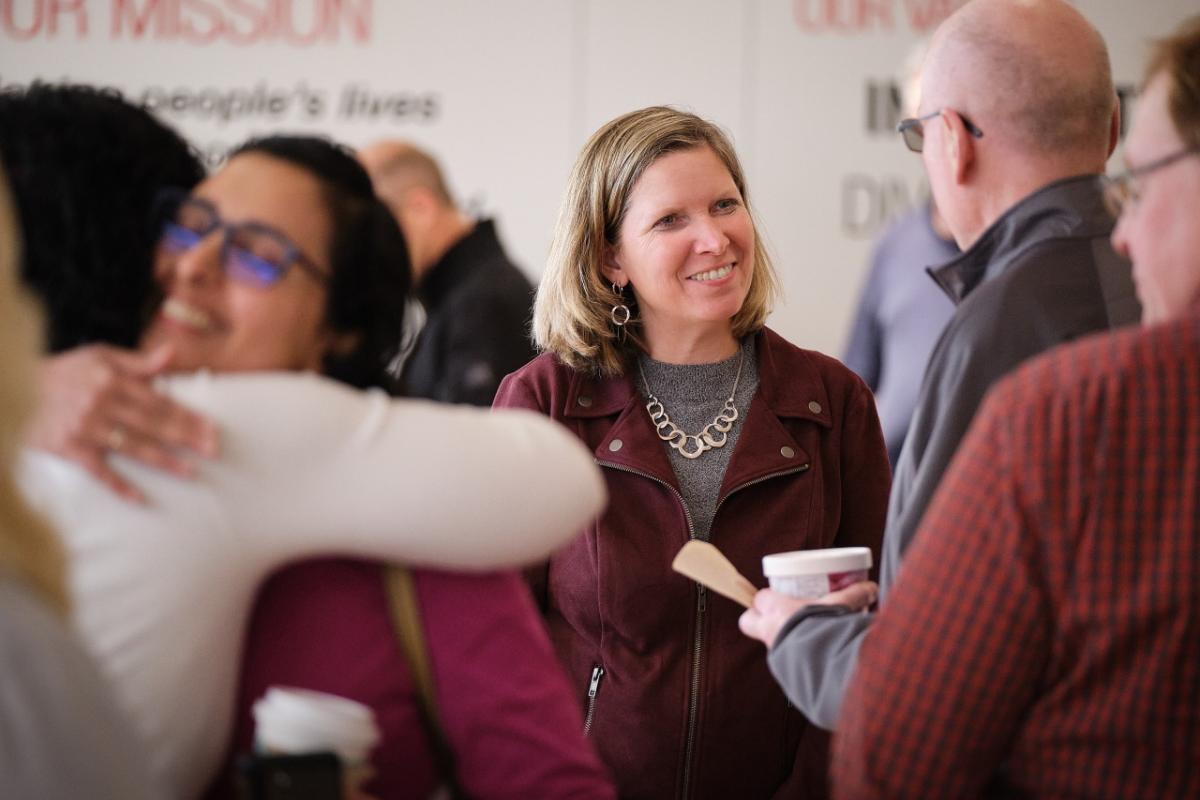 Jennifer Rumsey in a room of people, some hugging, some eating