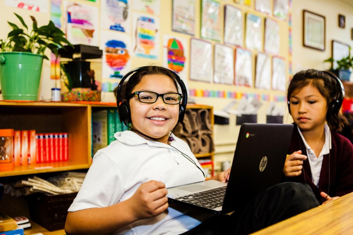 Child with headset using laptop