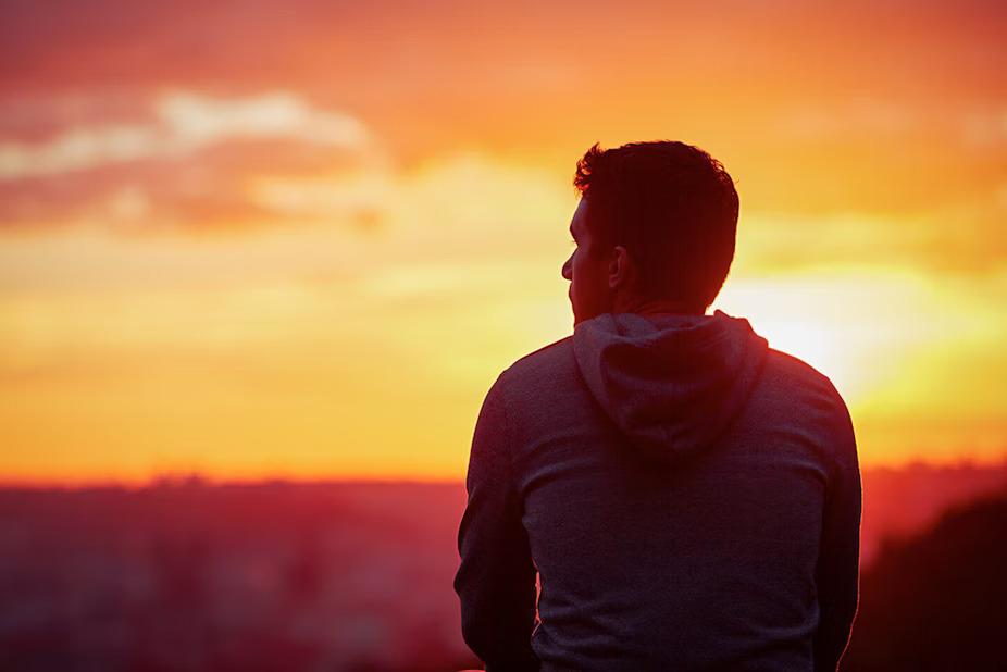 A person looking to the distance, a sunset over the horizon.