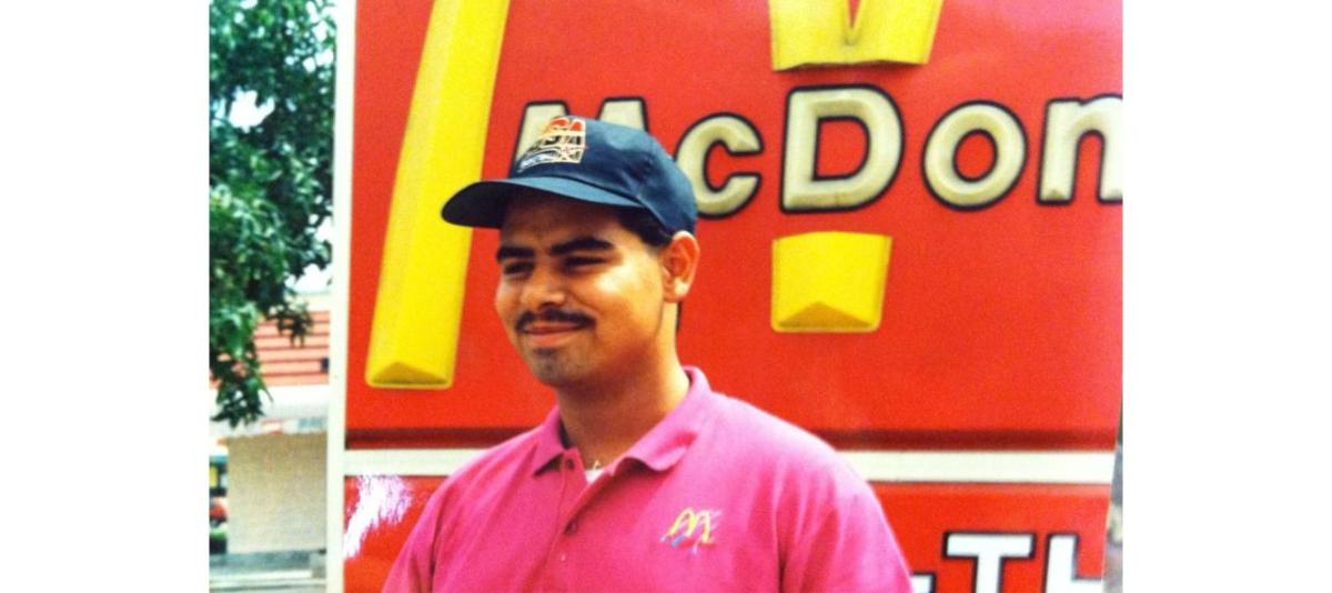 A young Juan Marquez outside by a McDonalds restaurant sign.