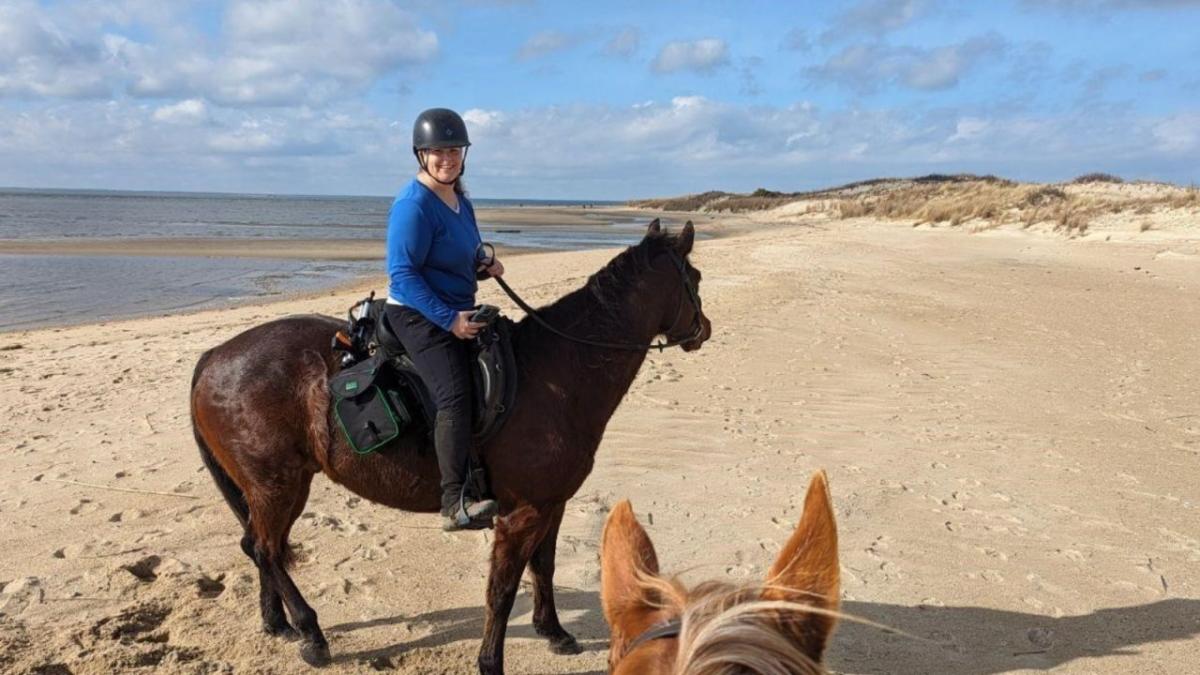 Julia Reilly riding a horse on a beach