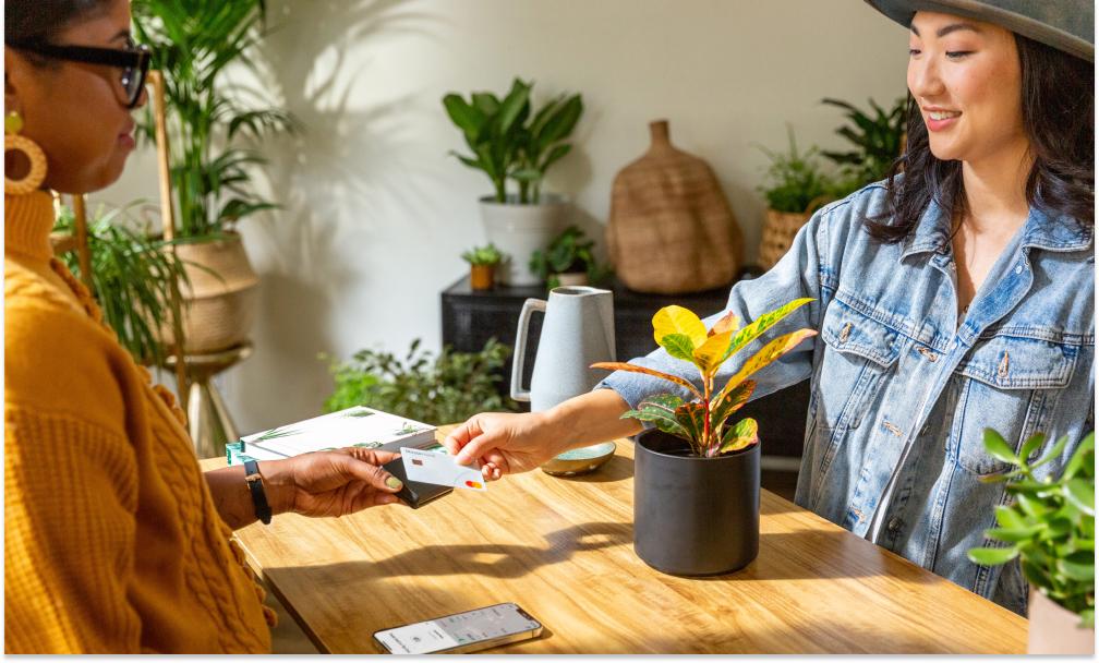 Kat Hernandez holding a card reader for a customer in a plant shop