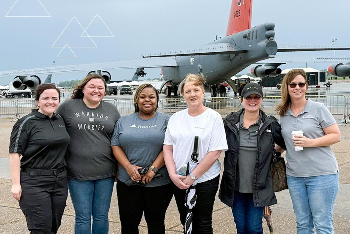 Kay Goke in group photo in front of large plane