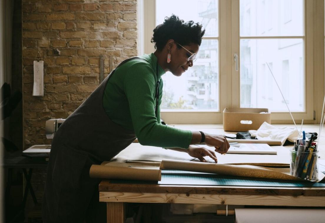 Woman shown standing at a desk reviewing paperwork.