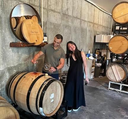 Kim shown in a vineyard with a cask of wine.