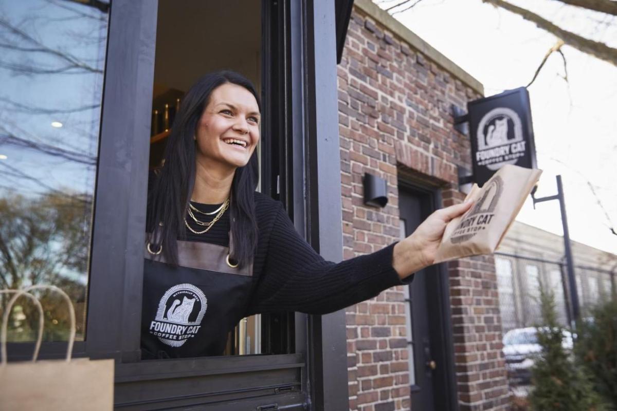 Kimberly Hoffmann leaning out a drive-thru window handing someone an item.