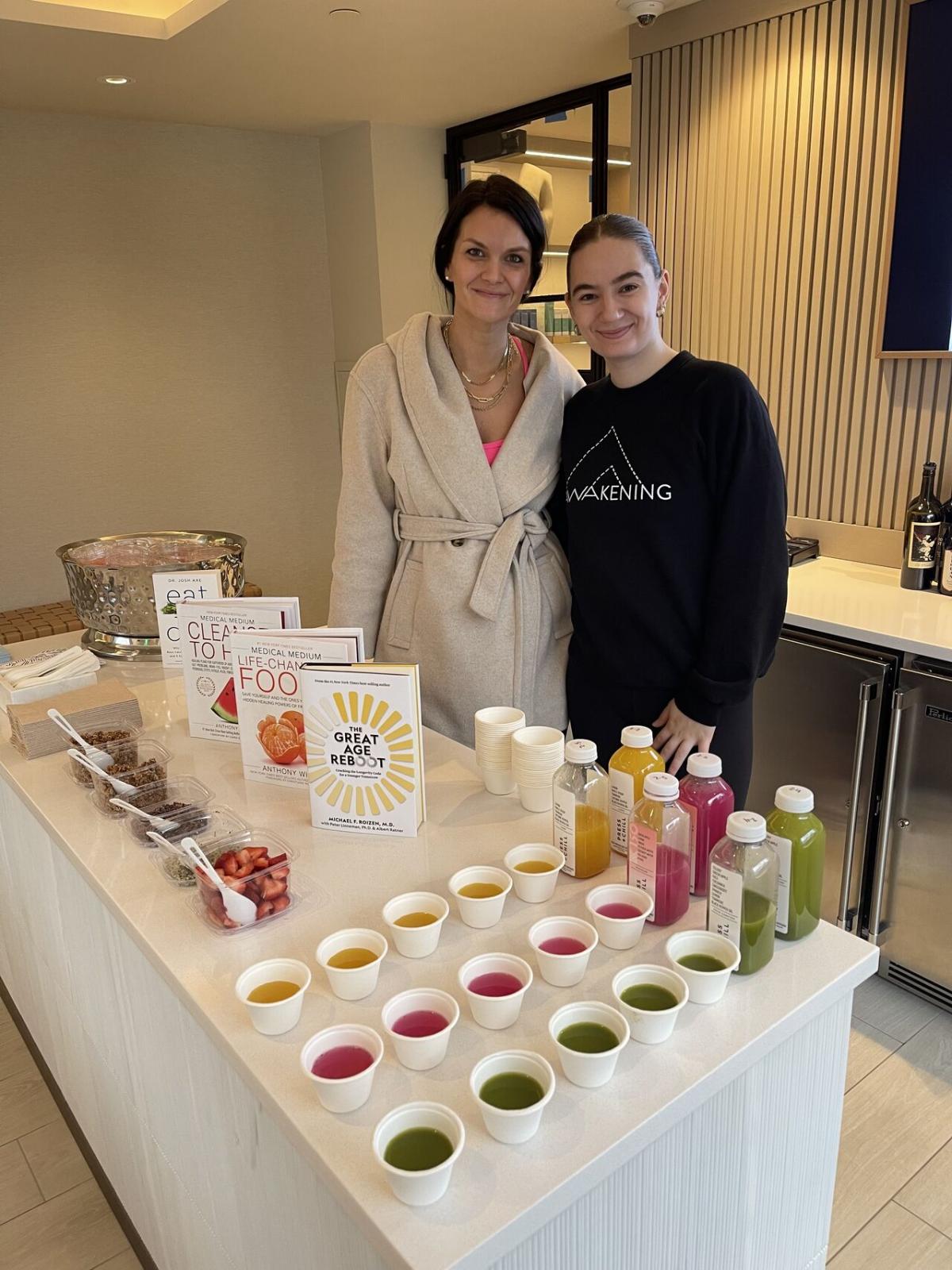 Kimberly Hoffmann and another behind a table with samples of drinks and foods.