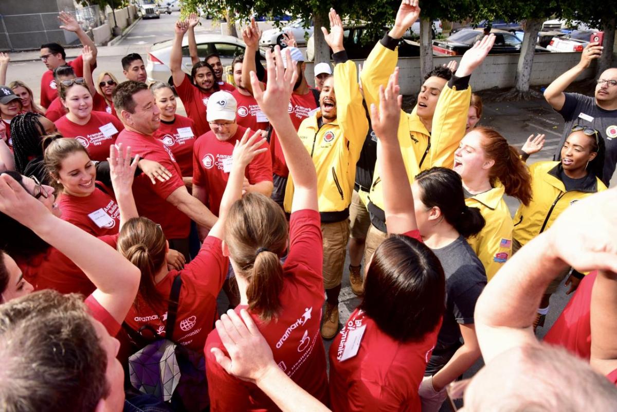 Volunteers raise their hands as a part of an outdoor “huddle”