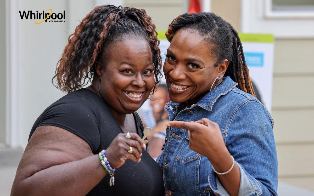 A woman in a denim jacket pointing to Latonya holding a house key