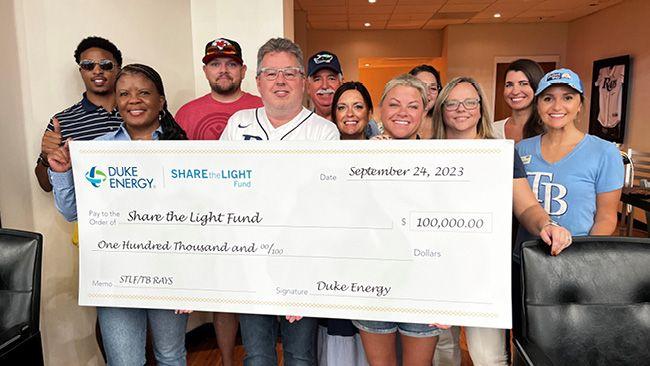 Groupd of people smiling while holding a cheque for $100,000