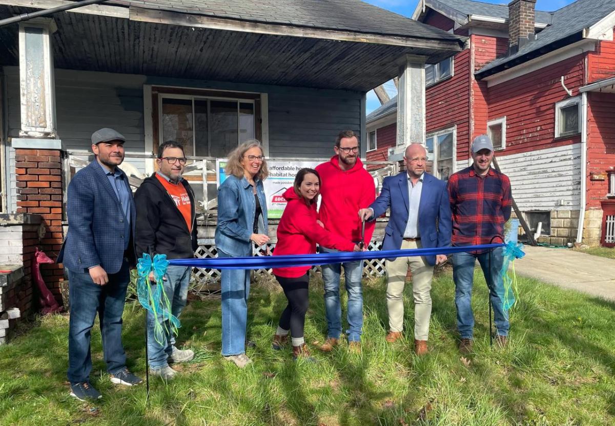 Group of people at a ribbon cutting in front of a home