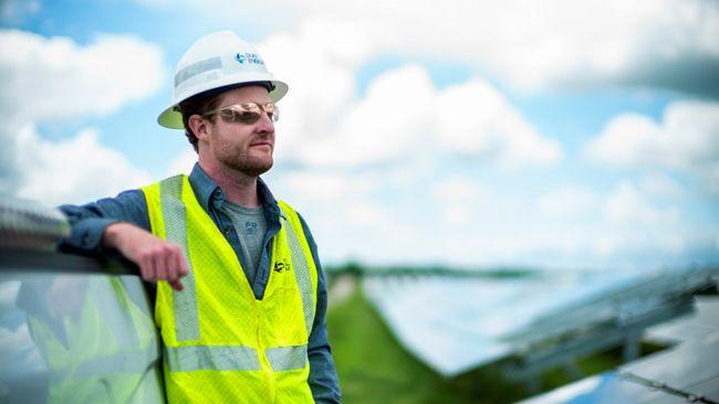 person in utility vest and sunglasses looking out