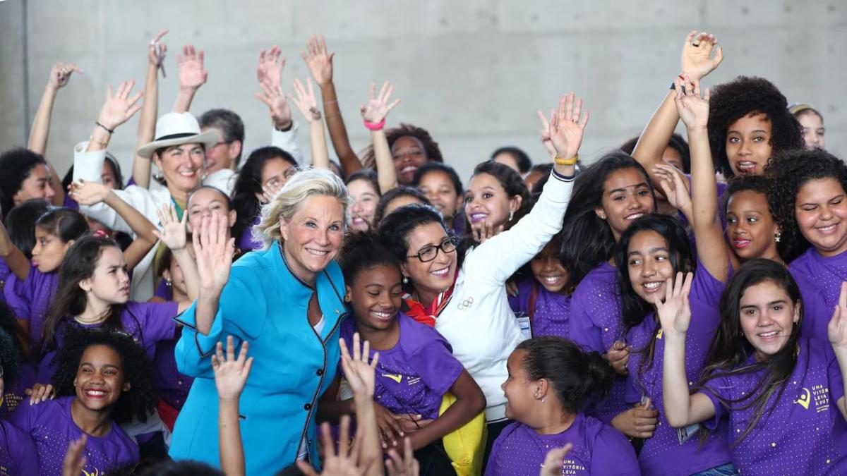 Lucia Prieto in a crowd of children waving to the camera.