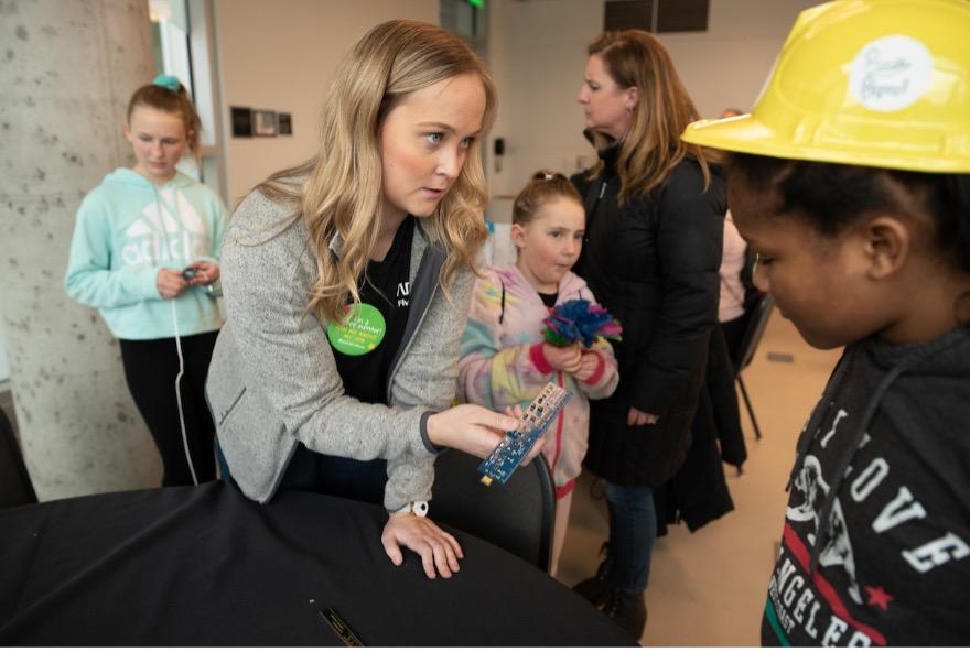 Maddie Eyolfson showing a young child a piece of equipment