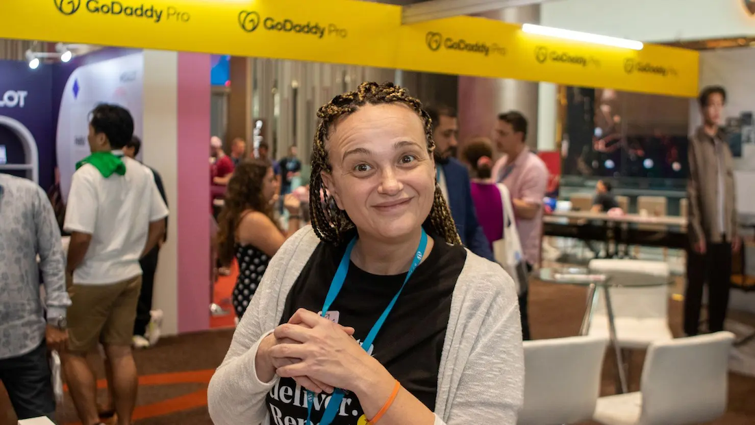 Maja smiling in front of the GoDaddy pro booth.