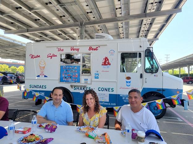 HARMAN people seated at a table with an ice cream truck in the background.