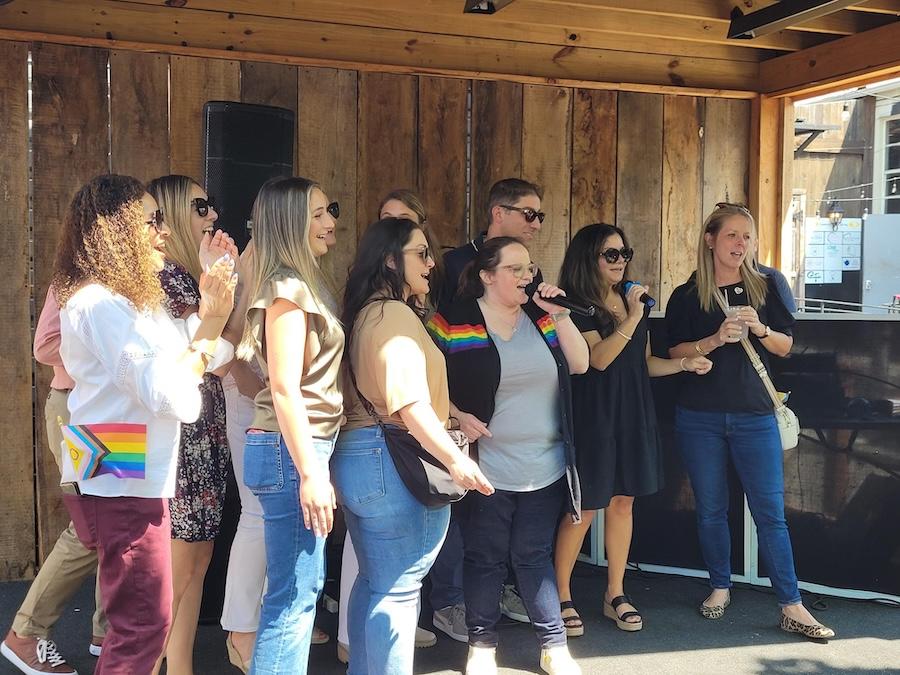 A group of HARMAN people in a circle singing.