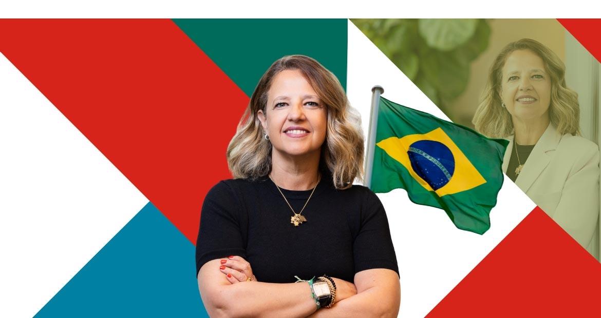 A person stood with their arms folded in front of a flag of Brazil