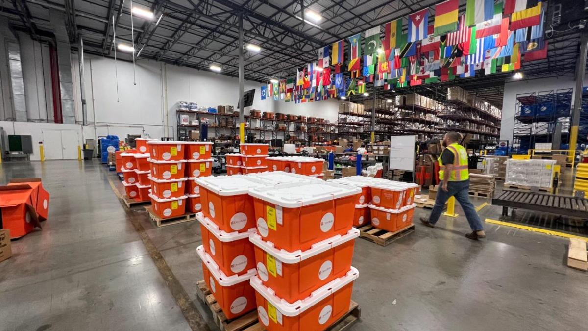 N-95 masks, wildfire kits, and other medical products from Direct Relief depart for Maui in response to wildfires. (Brea Burkholz/Direct Relief) orange tubs of medicine in a warehouse