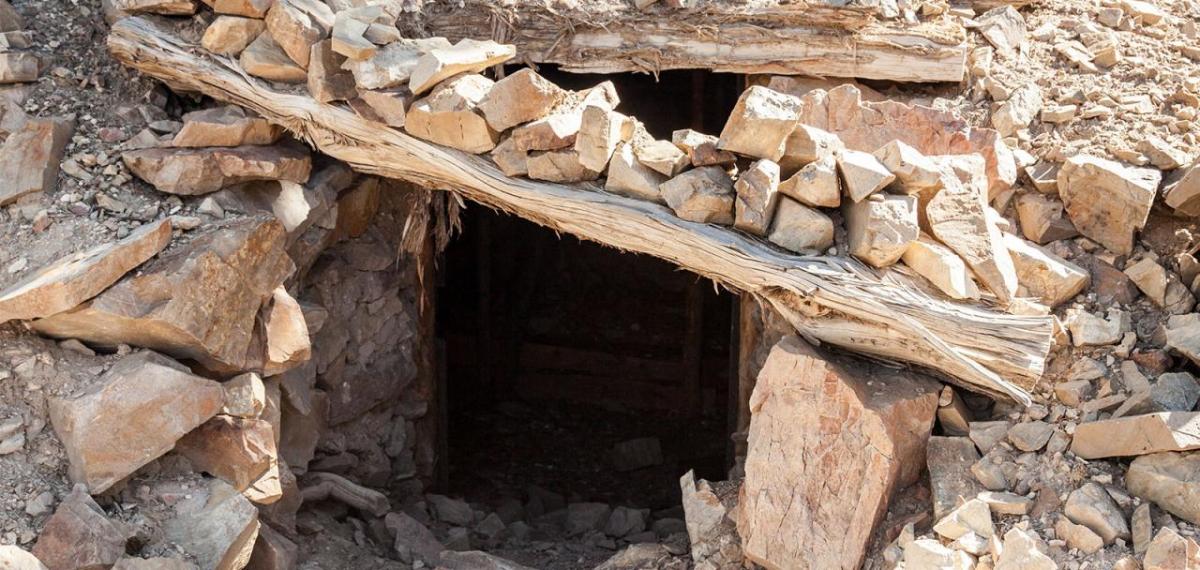 Opening to a mineshaft, rocks and wood create a doorway.