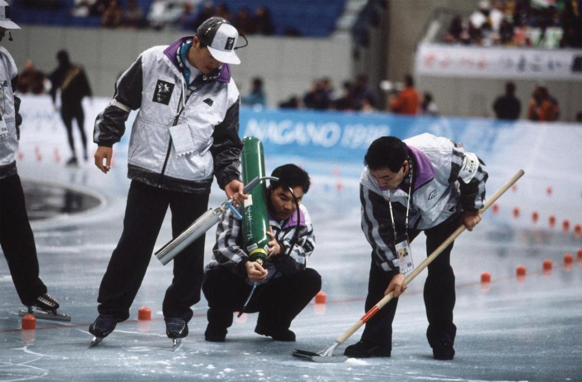 Three people doing a repair on a speed skate track.