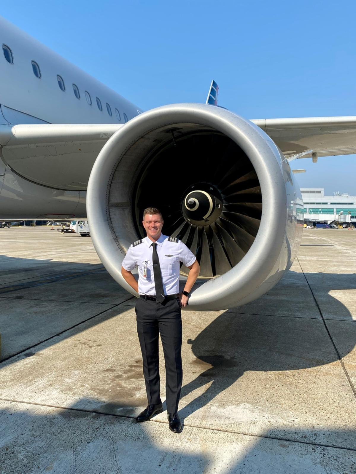 Pilot David Pettet standing in uniform in front of a plane engine